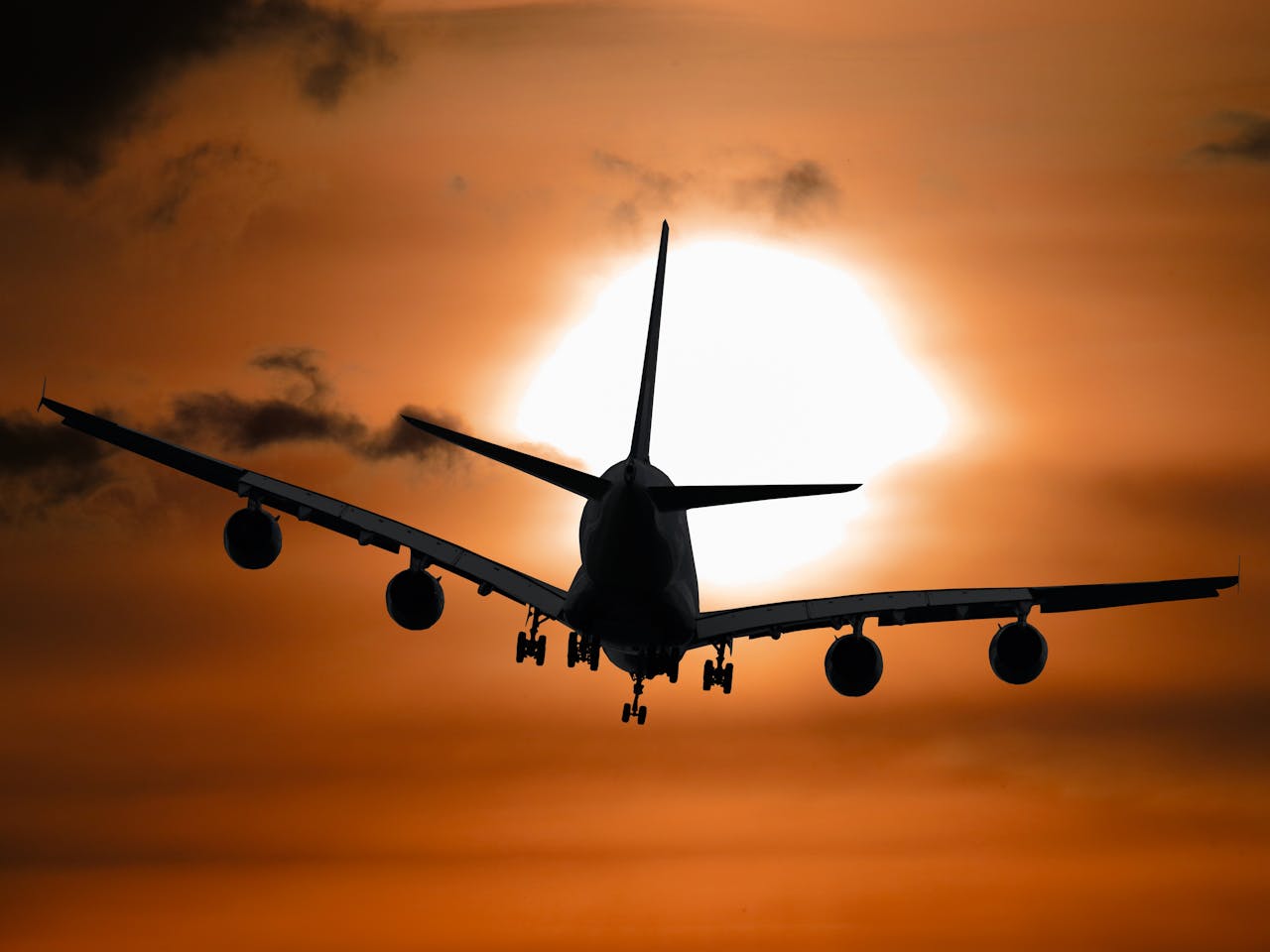 Dramatic silhouette of an airplane flying against a vibrant sunset sky.